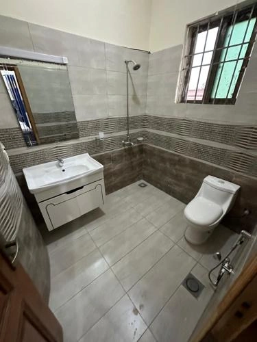 Modern guest house bathroom in Islamabad with tiled walls, shower area, sink vanity, and clean fixtures offering comfort for 2026 travelers.